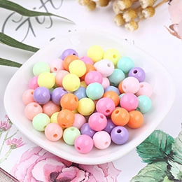 Macro shot of colorful macaron plastic beads for DIY jewelry making in a white dish