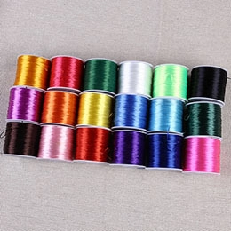 Flat lay view of 18 rolls of colorful elastic crystal jewelry cords for DIY beadwork