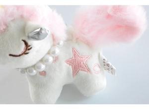 Close-up of plush unicorn pendant with pearl necklace and pink star embroidery details