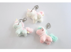 Three plush unicorn keychains with pearl necklaces in pink, white, and mint green