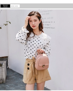 Pink leather mini backpack styled with a white polka dot chiffon top and khaki shorts