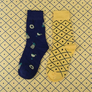 Detailed view of yellow and blue mid-calf socks with pineapple and cocktail patterns