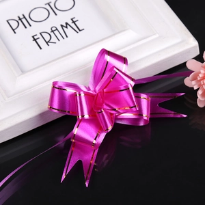 Detail of rose pink gift bow with gold edges and layered ribbon for festive packaging