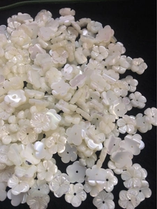 Macro shot of 10mm white shell flower charms with center holes for DIY jewelry making