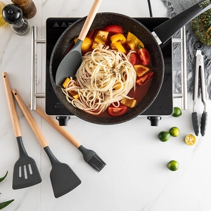 11-piece silicone kitchen utensil set with wooden handles on white marble countertop