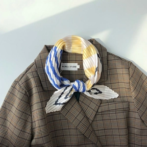 Detailed view of yellow blue and white pleated silk scarf tied on a suit collar