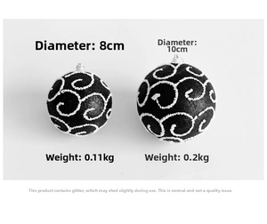 Detail of 8cm and 10cm black Christmas baubles with white glitter swirl patterns