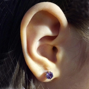 Close-up of a purple round-cut zircon earring featuring a 316 titanium steel crown setting