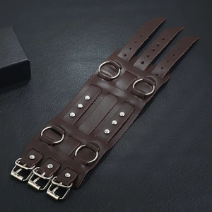 Macro shot of brown leather punk wristband featuring metal rings and buckle straps