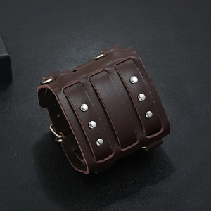 Close-up of wide dark brown leather punk cuff bracelet with metallic studs and buckle strap