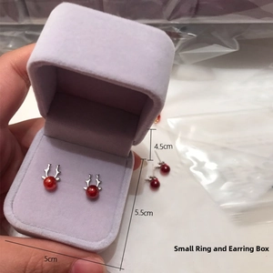 Macro detail of a 5x5.5cm purple velvet jewelry box holding festive reindeer stud earrings