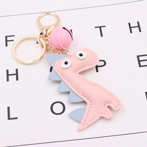 Detail of pink PU leather dinosaur keychain with blue fins, pink bell and gold metal ring