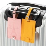 Detail of pink Eiffel Tower PU leather luggage tag and yellow tag on suitcase