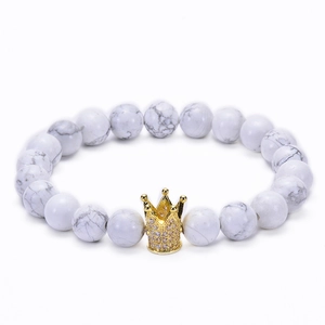 Close-up of 8mm white turquoise beads with a gold-plated cubic zirconia crown charm