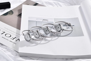 Detail of silver twisted cable bracelet watches on a Kinfolk style magazine background