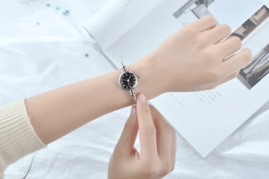 Elegant silver bangle quartz watch with black dial and Roman numerals on a female wrist