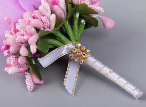 Macro shot of purple rose boutonniere with glittery pink berries and rhinestone ribbon