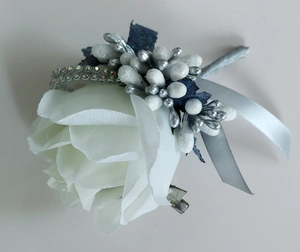 Detailed view of handmade white silk rose boutonniere with silver berries and navy leaves