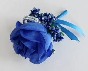 Detailed macro view of dark blue silk rose boutonniere with rhinestone accents and ribbon