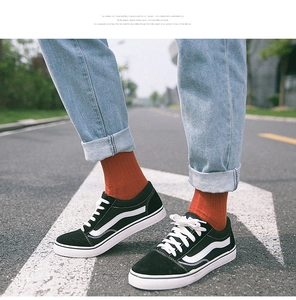Black low-top sneakers with white side stripes paired with casual orange cotton socks