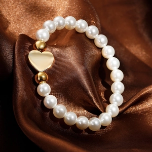 Elegant white pearl bracelet with golden heart pendant on luxurious dark silk background