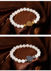 Detail of shell pearl bracelet with heart pendant in gold and silver on silk