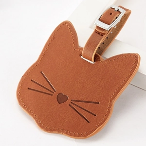 Close-up of brown leather cat-shaped luggage tag with fine stitching and silver buckle