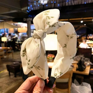 Detail of wide knotted headband with green floral embroidery on cream fabric