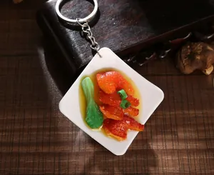 Macro view of miniature food keychain with braised meat and green vegetable on a plate