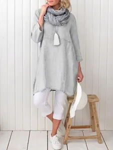 Detalle de blusa de algodón lino gris claro con pantalones blancos cortos y bufanda