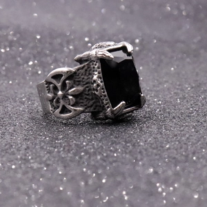 Macro shot of rectangular black gemstone ring with gothic cross carving on side