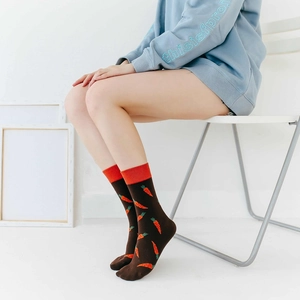 Detailed view of dark brown crew socks with carrot pattern on legs of a female model