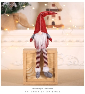 Detail of a sitting Christmas gnome with a red felt hat and striped legs on wood