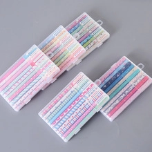 Primo piano di 5 set creativi da 12 penne colorate in scatole regalo trasparenti su grigio