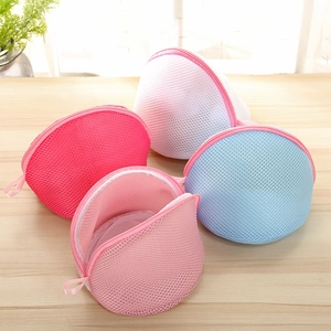 Detailed view of semi-cylindrical mesh laundry bags in four pastel colors on wood