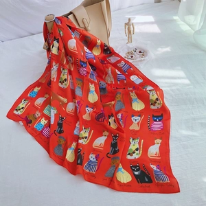 Detail of red silk-like square scarf featuring colorful cartoon cat illustrations