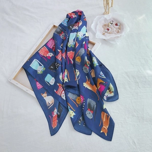 Detail showing playful cat prints on a 90cm navy blue silk scarf hanging on a wooden frame