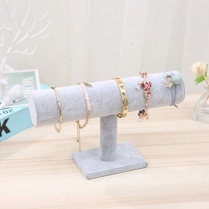 Macro shot of light gray velvet T-bar stand displaying bracelets on a wood table