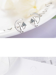 Macro shot of silver cat on moon earrings with sparkling zircon on a white ceramic tray