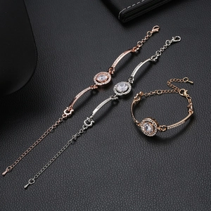 Detailed view of rose gold and silver rhinestone bracelets on a black leather texture