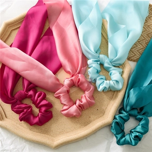 Detail of four colorful satin scrunchies with streamers in a stylish decorative tray