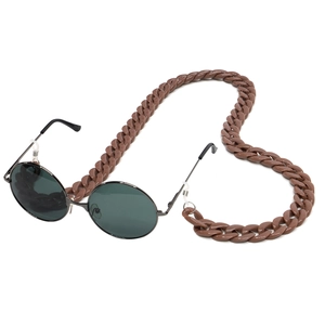 Detail of round sunglasses with a chunky brown acrylic chain strap and black metal frames