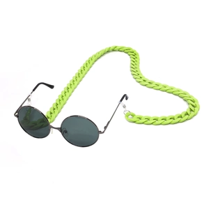Detail of vintage black sunglasses paired with a bright green acrylic mask and eyewear chain