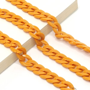 Detail of chunky orange acrylic chain links on a white book with a diagonal layout