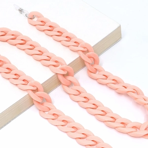 Detail shot of chunky peach pink acrylic chain link on a book with a clean white background