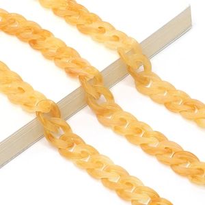 Macro view of orange tortoiseshell acrylic eyeglass chain over a white book