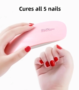 Macro shot of pink SUNmini portable UVLED nail lamp curing multiple fingernails at once