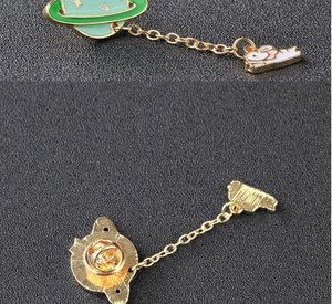 Detail of green planet and white rabbit enamel pin set with connecting gold chain