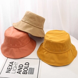 Drie zonnehoeden in beige, oranje en geel met details van letters in reliëf