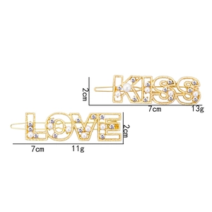 Golden KISS and LOVE hair clips set with pearls and rhinestones on white background